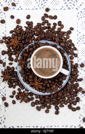 Composition of a coffee cup with spreaded beans and star anise. Stock Photo