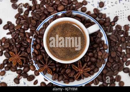 Composition of a coffee cup with spreaded beans and star anise. Stock Photo