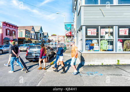 Bar Harbor, USA - June 8, 2017: Young people crossing street in downtown village on vacation in summer with skateboard Stock Photo