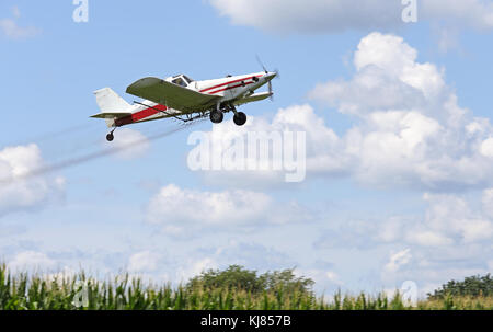 Airplane spraying pesticides over a corn field Stock Photo