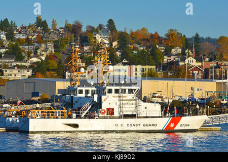 U.S. Coast Guard boat sits in Bellingham Bay just below the city of Fairhaven, Washington.  Fairhaven is a part of Bellingham, Washingotn and the hill Stock Photo