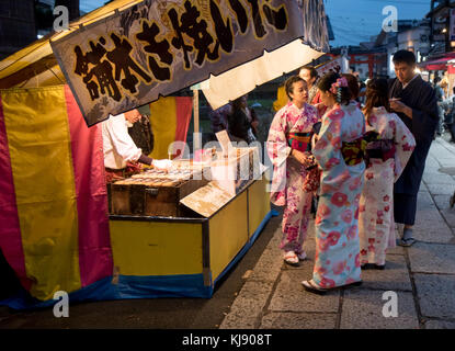 JAPAN, KYOTO, NOV 19 2016, Group of geisha buys at a kiosk on the street beside a Buddhist temple Inari Shrine, Kyoto, Japan Stock Photo