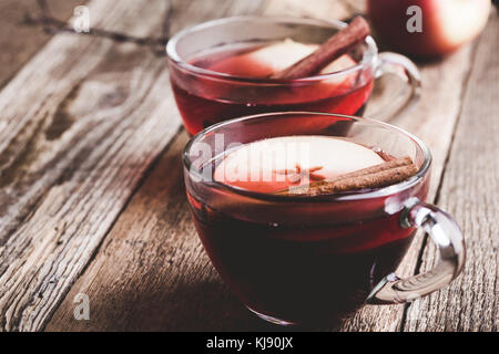 Mulled wine with apple slices in glass mugs on rustic wooden table served for two persons Stock Photo
