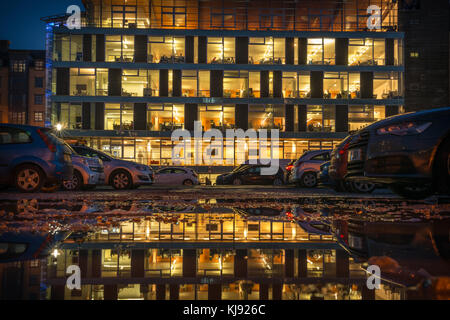 A low point of view over a puddle looking towards an office building from a car park on Dale Street, central Manchester. Stock Photo