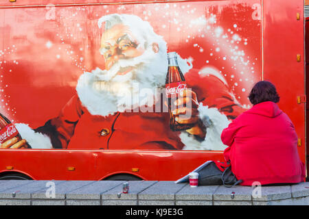 Bournemouth, Dorset, UK. 23rd Nov, 2017. The Christmas Coca Cola truck arrives at the Triangle in Bournemouth, as part of its Holidays are Coming Christmas campaign festive tour visiting locations around the country. Woman sitting on wall by truck Credit: Carolyn Jenkins/Alamy Live News Stock Photo