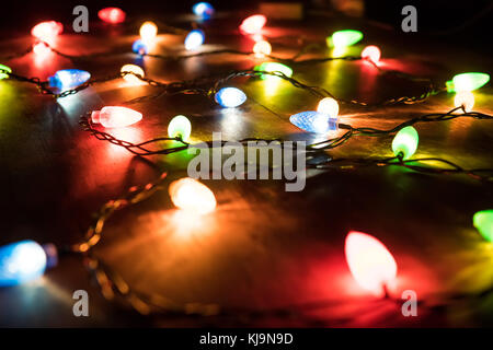 The light of the colored lights of the garland in the darkness. Colored lights on a Christmas garland in the dark of night Stock Photo