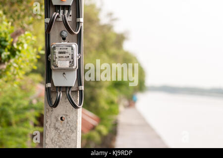 Electricity meter installed in the atmosphere of the waterfront in thailand Stock Photo