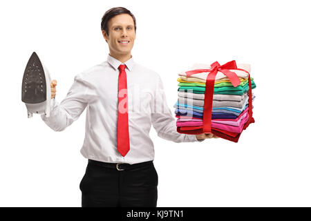 Elegant guy holding an iron and a stack of ironed and packed clothes wrapped with red ribbon as a present isolated on white background Stock Photo