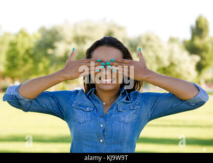 Outdoor portrait of a beautiful African American woman covering eyes with hands Stock Photo