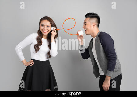 Young asian couple with can phone isolated on gray background Stock Photo
