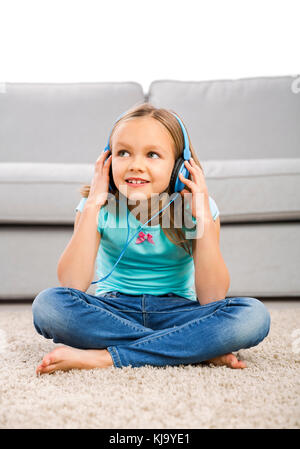 Little blonde girl at home listen music with headphones Stock Photo