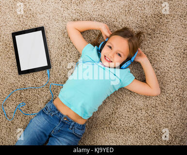 Little blonde girl at home listen music with headphones Stock Photo