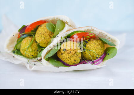 Baked falafel and fresh vegetables in pita bread, light background. Stock Photo