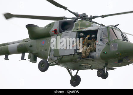 British army personnel look out of a AgustaWestland Lynx Helicopter in flight. Stock Photo