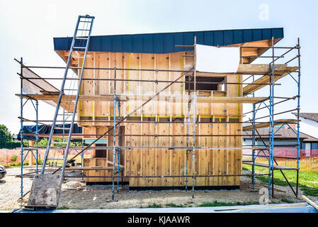 Building energy efficient passive wooden house. Construction site and exterior of a wooden panel house with scaffolds ready for wall insulation. Stock Photo