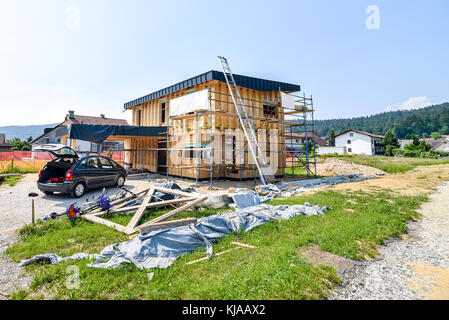 Building energy efficient passive wooden house. Construction site and exterior of a wooden panel house with scaffolds ready for wall insulation. Stock Photo