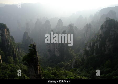 Hazy sunset over the Zhangjiajie National Forest Park's rugged peaks and limestone pillars in Hunan province at China Stock Photo