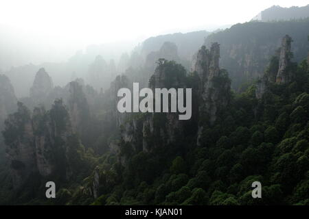 Hazy sunset over the Zhangjiajie National Forest Park's rugged peaks and limestone pillars in Hunan province at China Stock Photo