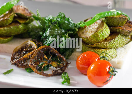 Baked zuccini  with cherry tomatoes and green pepper on white bread. Baked lemon Stock Photo