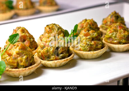 Tartlets with baked vegetables and herbs on white porcelain dish Stock Photo