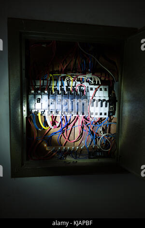 LED flashlight torch lamp illuminating part of old circuit breaker  switch, cables and wires on panel is seen inside house, Asuncion, Paraguay Stock Photo