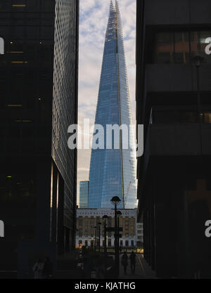 A view of the Shard between the silhouettes of surrounding buildings. The Shard is an iconic skyscraper in a financial district of Southwark, London. Stock Photo