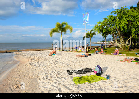 People sunbathing on the artifical sandy beach by The Lagoon on the Esplanade, Cairns, Far North Queensland, FNQ, QLD, Australia Stock Photo