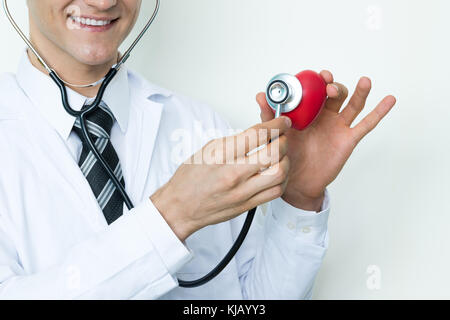 Diabetes and Smart Healthcare technology concept. Professional man smile doctor using stethoscopes to measure red heart in hospital. Stock Photo