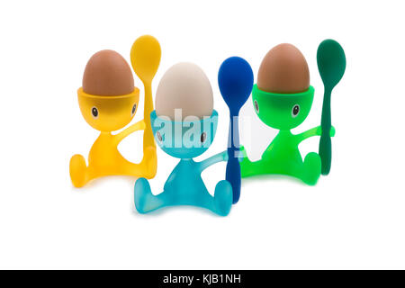 Three boiled eggs in colourful children's character egg cups, cutout on white background. Stock Photo