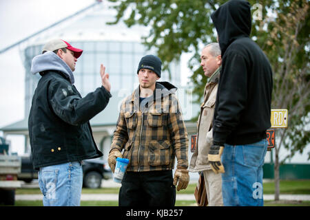 FARMER AND SONS TALKING ABOUT HARVEST ON THE FAMILY FARM IN BLOOMING PRAIRIE, MINNESOTA. Stock Photo