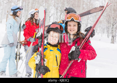 Portrait of smiling Caucasian brother and sister carrying skis Stock Photo