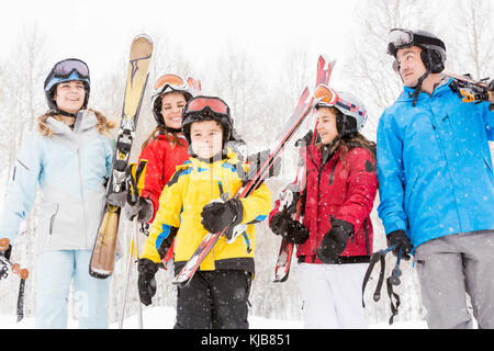 Smiling Caucasian family carrying skis in snow Stock Photo