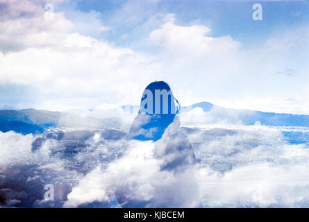 Double Exposure of a woman looking out at distant mountains under a winter sky filled with clouds Stock Photo