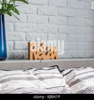 Decorative relax sign in new bedroom with double bed and brick wall Stock Photo