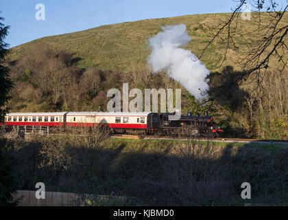 Preserved former LMS and BR Ivatt Class 2 2-6-2T steam locomotive  No.41312 nears Corfe Castle Station on the Swanage Railway with a passenger train Stock Photo
