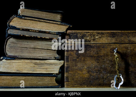 Old rolls and plans in folded paper rolls. Old book and case. Documents on an old wooden table. Black background. Stock Photo