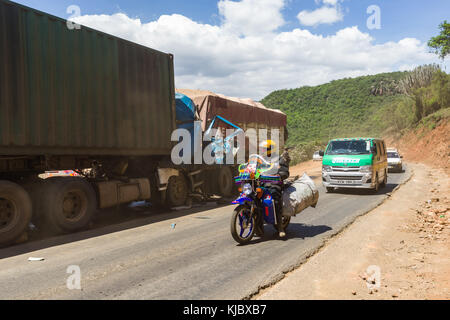 Vehicles drive past the aftermath of a road traffic accident involving two lorries on a Rift Valley road, Kenya, East Africa Stock Photo