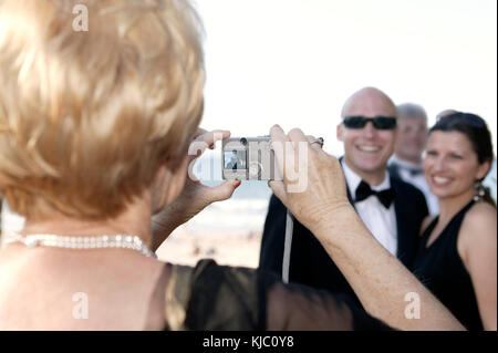 Woman Taking Couple's Portrait at Wedding Stock Photo