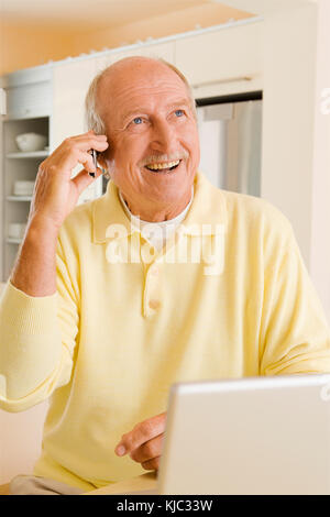 Man Talking on Cell Phone, Using Laptop Computer Stock Photo