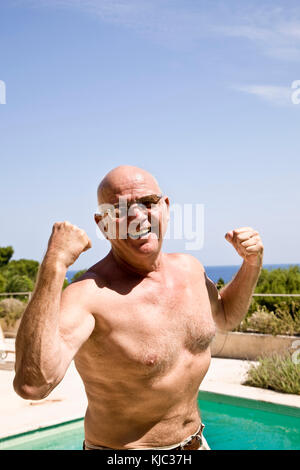 Portrait of Man by Swimming Pool Flexing His Muscles Stock Photo