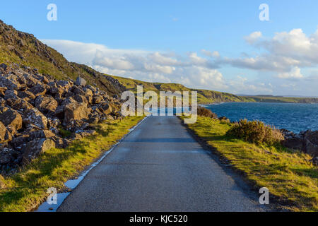 Typical Scottish landscape of the Isle of Sky with a coastal road and sea cliffs on a sunny day in Scotland, United Kingdom Stock Photo