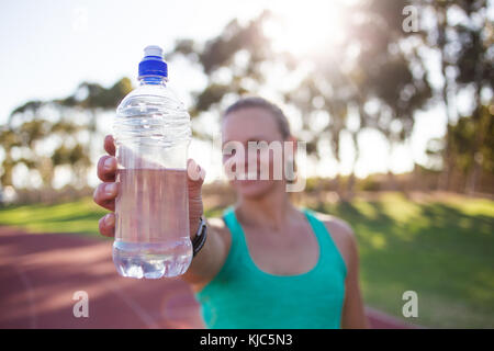 Close up wide angle view of a female sprinter athlete getting ready to start a race on a tartan racetrack with dramatic lighting late in the afternoon Stock Photo