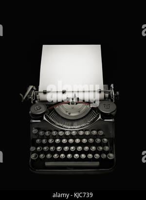 Low key edition of an ancient typewriter integrated on black background to give prominence at white page Stock Photo