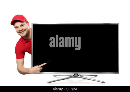 smiling young man in red uniform pointing on blank tv screen Stock Photo