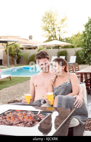 Caucasian couple wrapped in towels near fire pit Stock Photo