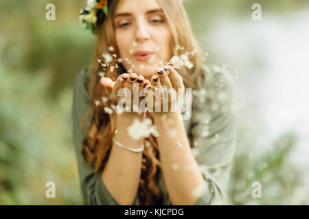 Middle Eastern woman blowing dandelion seeds Stock Photo