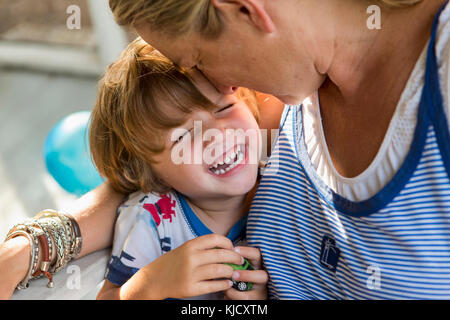 Caucasian mother hugging laughing son holding toy car Stock Photo