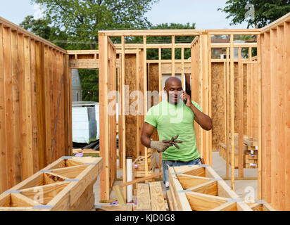 Volunteer building house talking on cell phone Stock Photo