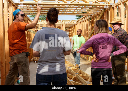 Volunteers talking while building a house Stock Photo