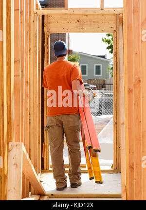 Caucasian man carrying ladder at construction site Stock Photo